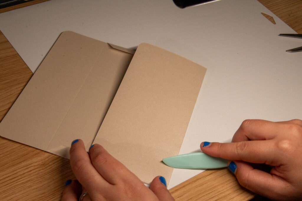 Using a boning tool to crease the bottom flap of the envelope. 